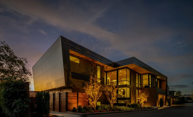 A Hamish Anderson waterfront house at twilight, its windows lit
